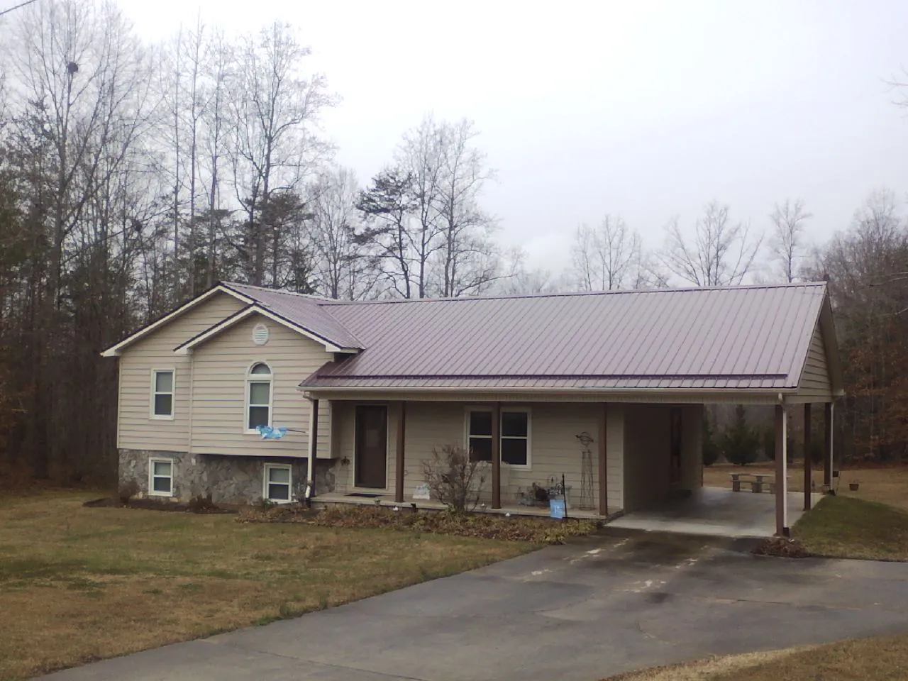 Burgundy metal roof on a tan split level home with an attached carport in North Troy