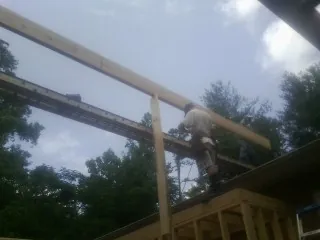 Carpenter setting a ridge beam over a new addition frame — Ice Dam Removal by Roofing Brothers in North Troy