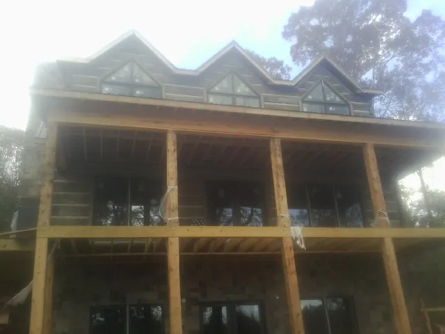 Dormers and porch framing on a large log home under construction — Roof Coating work by our crew in North Troy