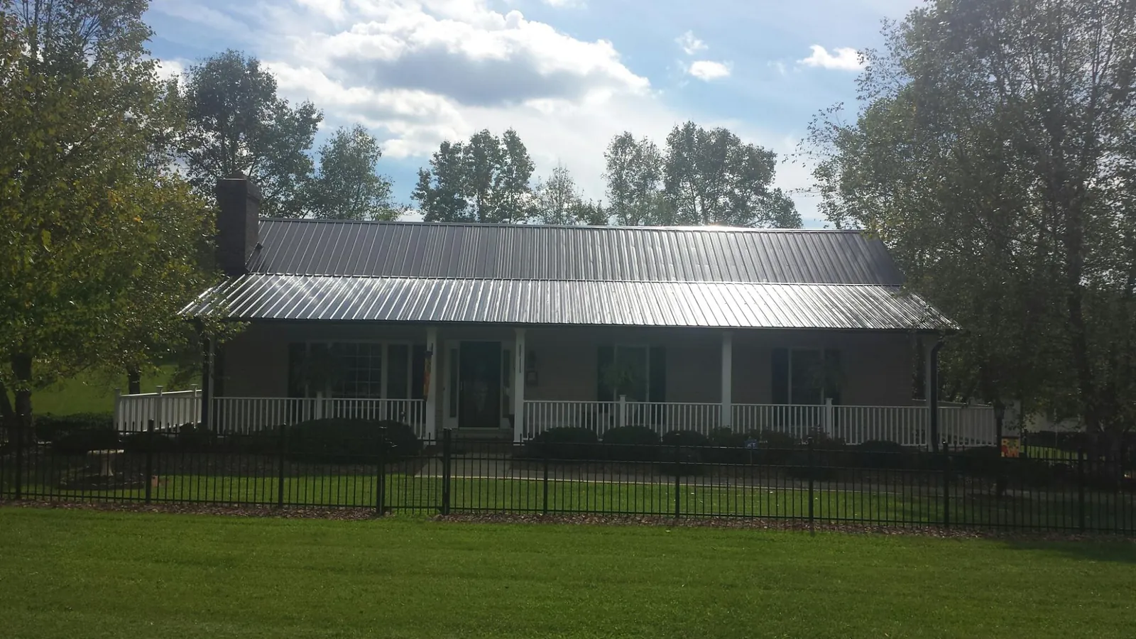 Gray metal roof on a brick ranch with a full width front porch — Gutter Guard Installation work by our crew in North Troy