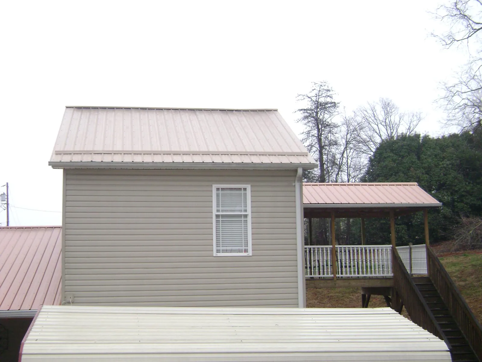 Tan metal roofs on a two story addition and attached porch, from a Roof Replacement job in North Troy