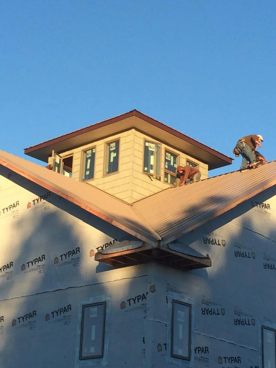 Roofers working around a rooftop cupola on a new metal roof at sunset — Roof Waterproofing in North Troy by Roofing Brothers